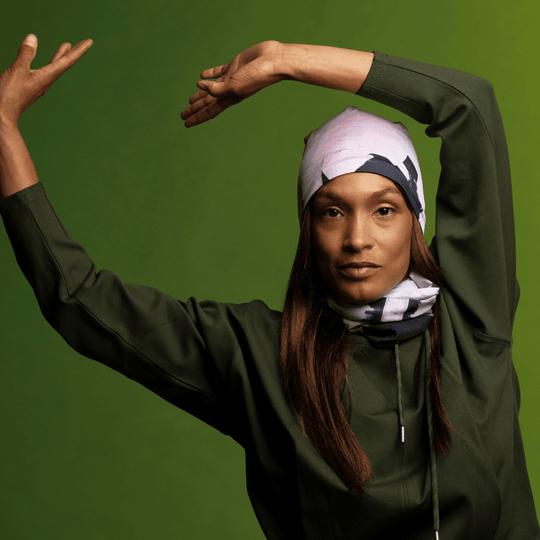 Model in a dark green top, posing with arms raised, wearing the modern quilt print as a bandana.