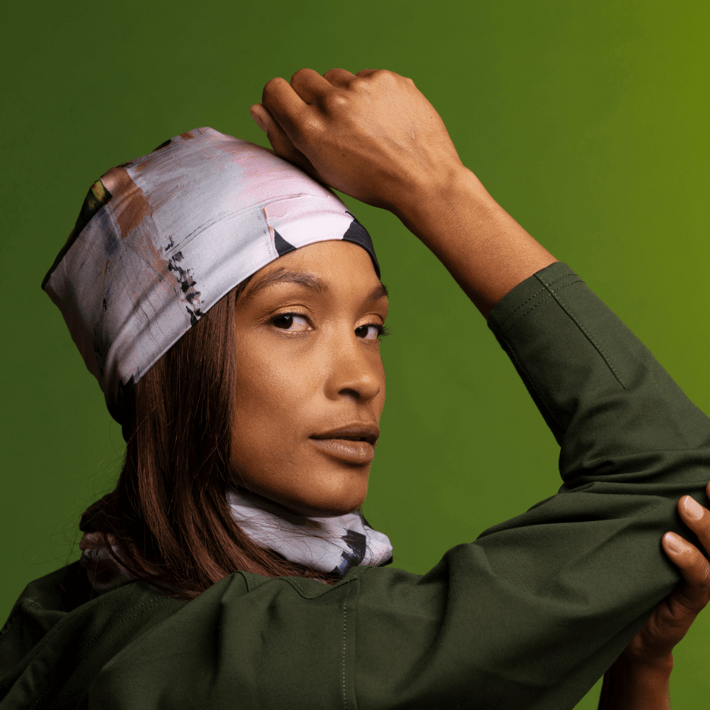 Model wearing a modern quilt print as a bandana and neck gaiter against a green background.