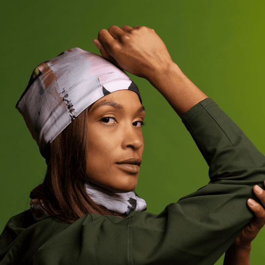 Model wearing a modern quilt print as a bandana and neck gaiter against a green background.