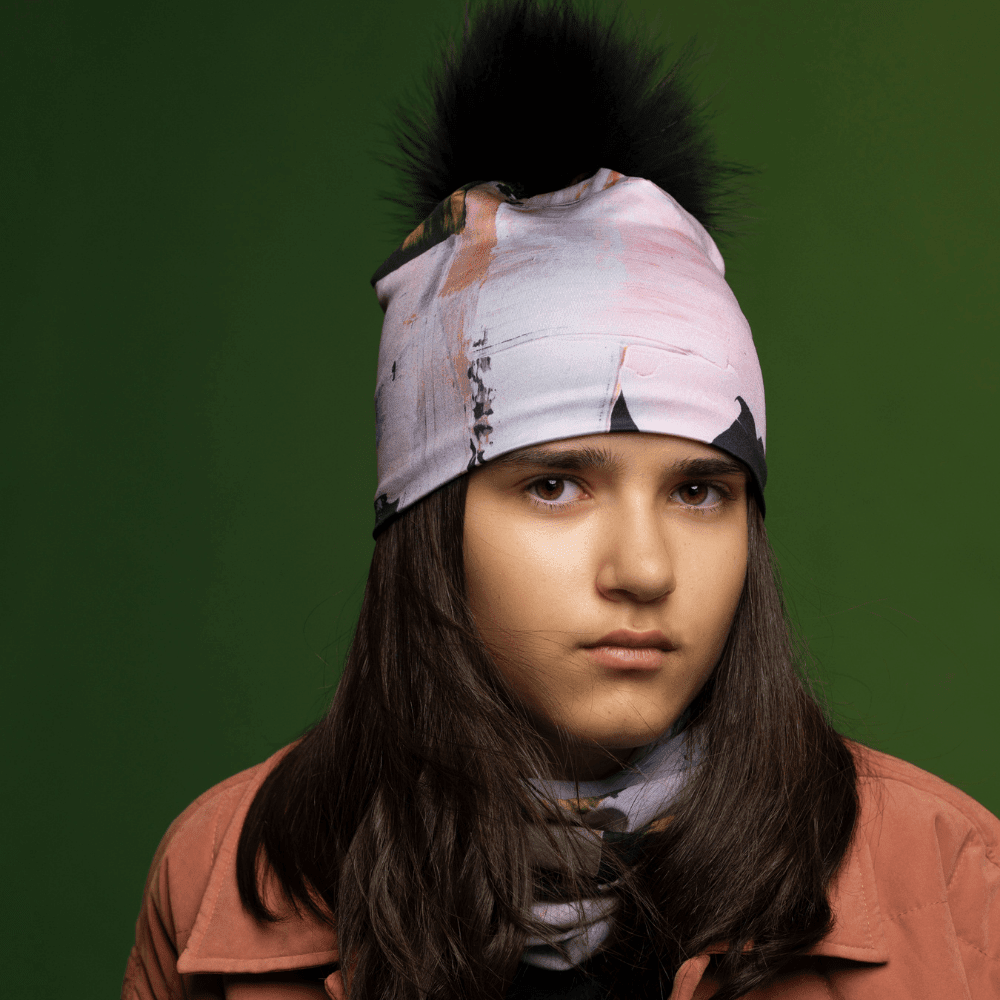 Close-up portrait of a young person wearing a beanie with a black pompom