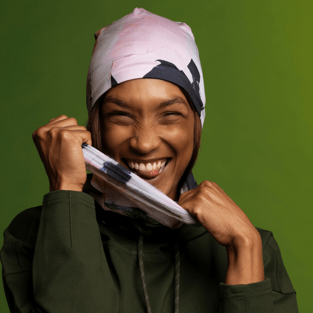 Close-up of a smiling woman pulling the Modern Quilt Multifunctional Tube away from her face, showcasing the abstract art design.