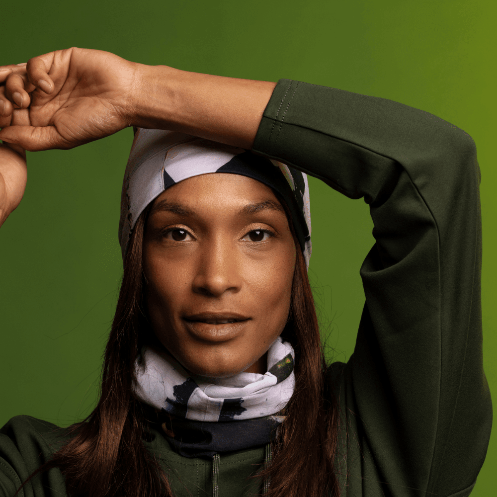 Woman wearing a matching olive green hoodie and beanie, with the Modern Quilt Multifunctional Tube around her neck.