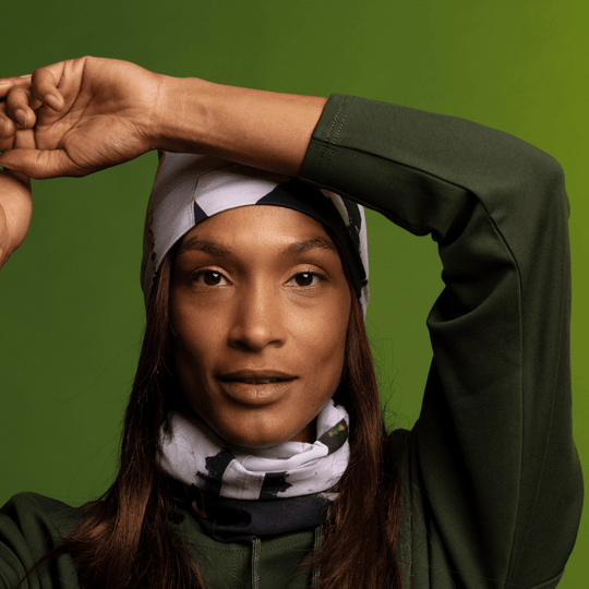Woman wearing a matching olive green hoodie and beanie, with the Modern Quilt Multifunctional Tube around her neck.