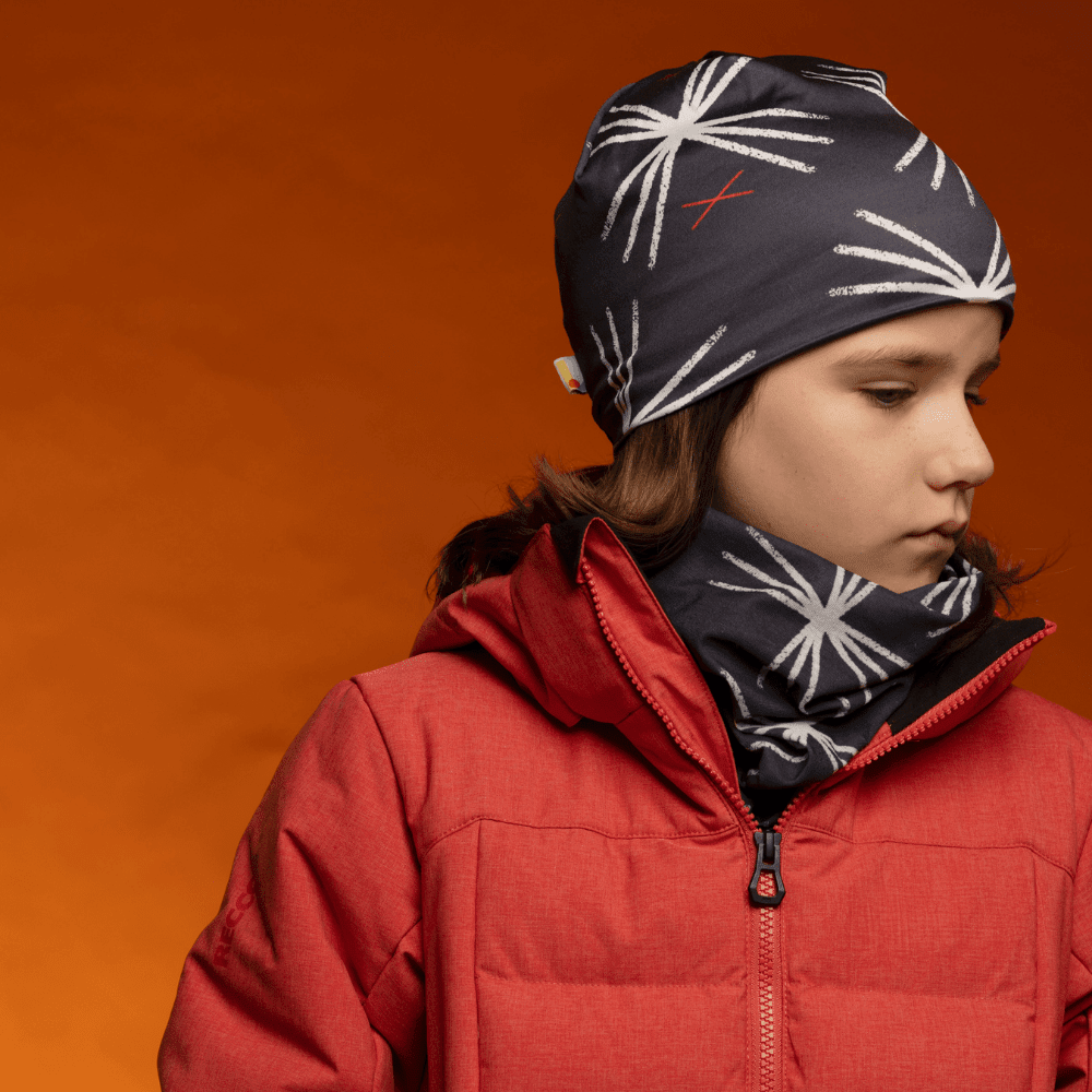 A young person wearing the MotifX Black Beanie and a matching neck gaiter with a red winter jacket.
