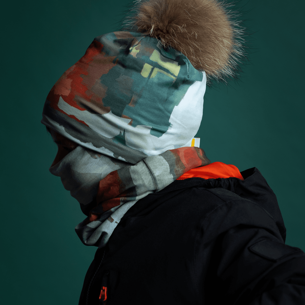 Model wearing a black winter jacket with a beanie and neck gaiter featuring a colorful abstract art print.