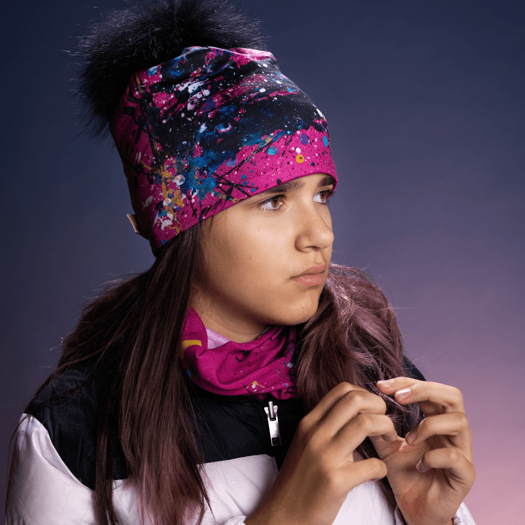 Teenage girl wearing a pink and black abstract art beanie and a matching pink neck gaiter.