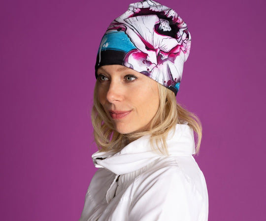 Woman wearing the New Poppy Beanie for Girls and Women, showcasing its artistic floral design against a purple background.