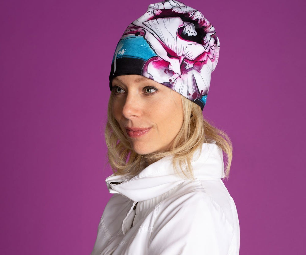 Woman wearing the New Poppy Beanie, which features a colourful floral design and a black pom pom.