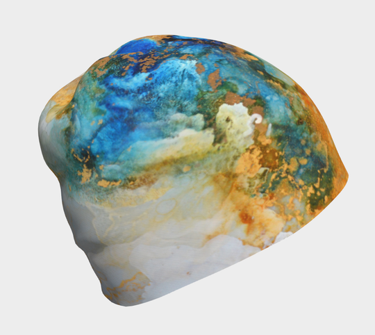 Close-up of a soft beanie displaying a marbled ocean pattern with blue, green, and gold accents.