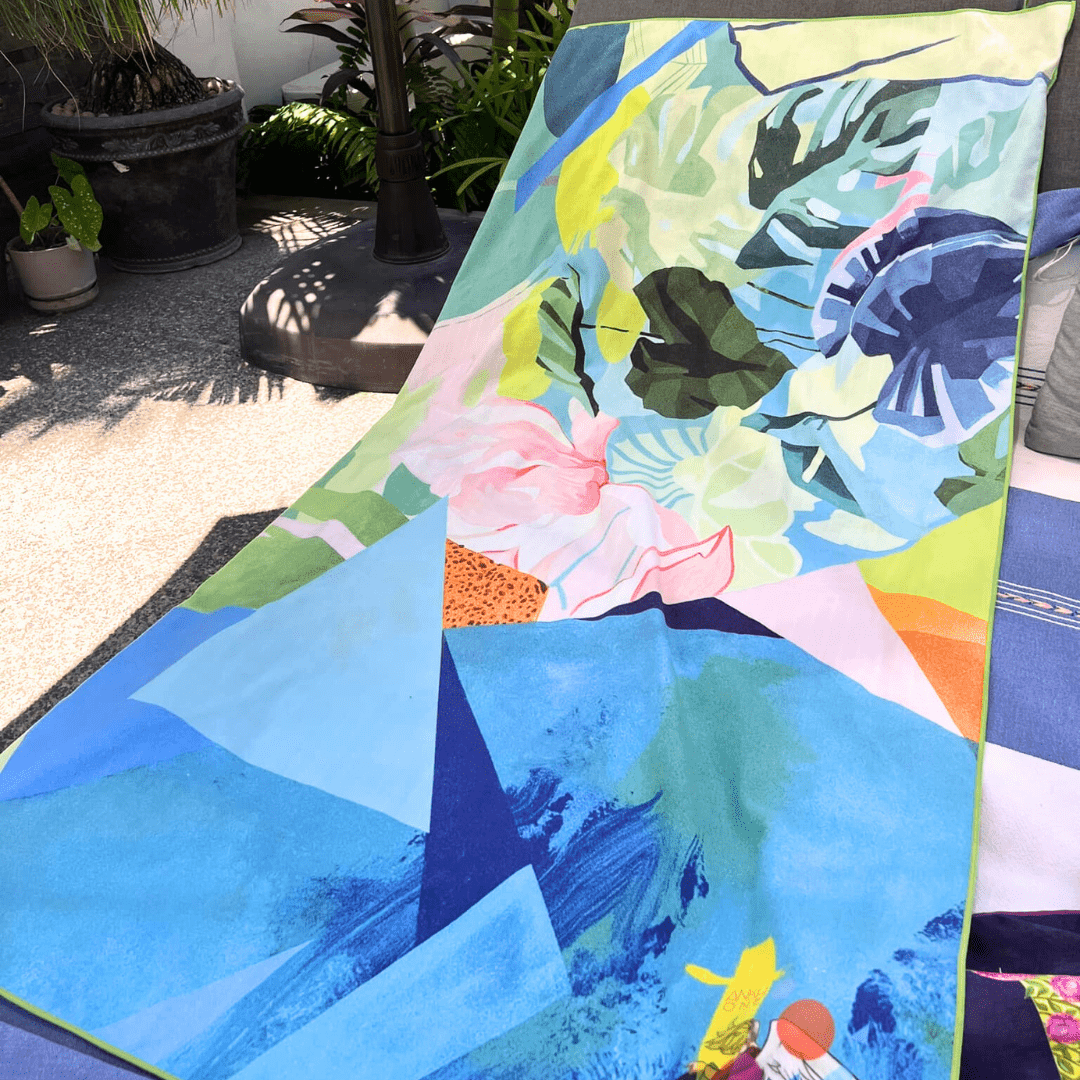 A colourful abstract floral microfiber towel draped outdoors on a lounge chair.