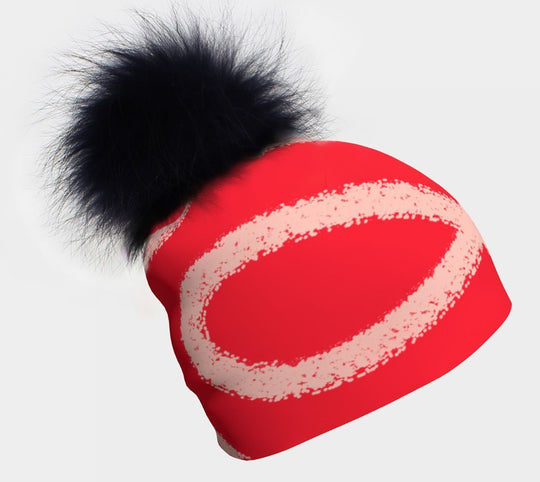 Peachy-Red Beanie with a large, fluffy black pompom on top.