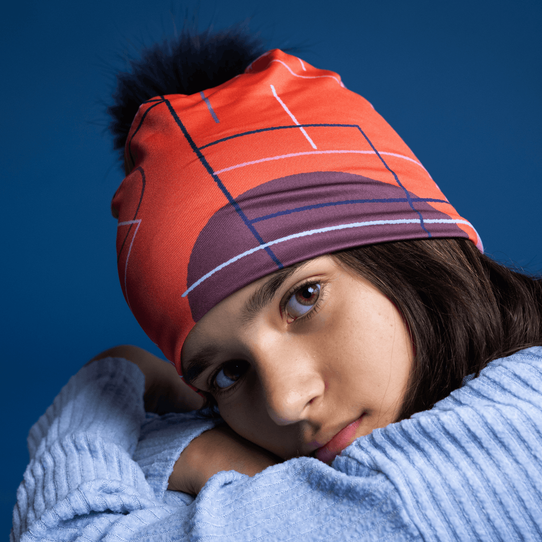 Close-up portrait of a young girl wearing the Pink Graphicometrics Beanie, resting her chin on her arms.