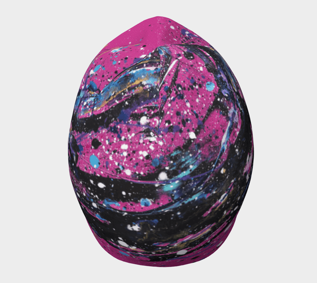 A pink beanie with an abstract paint splatter design, viewed from the top.