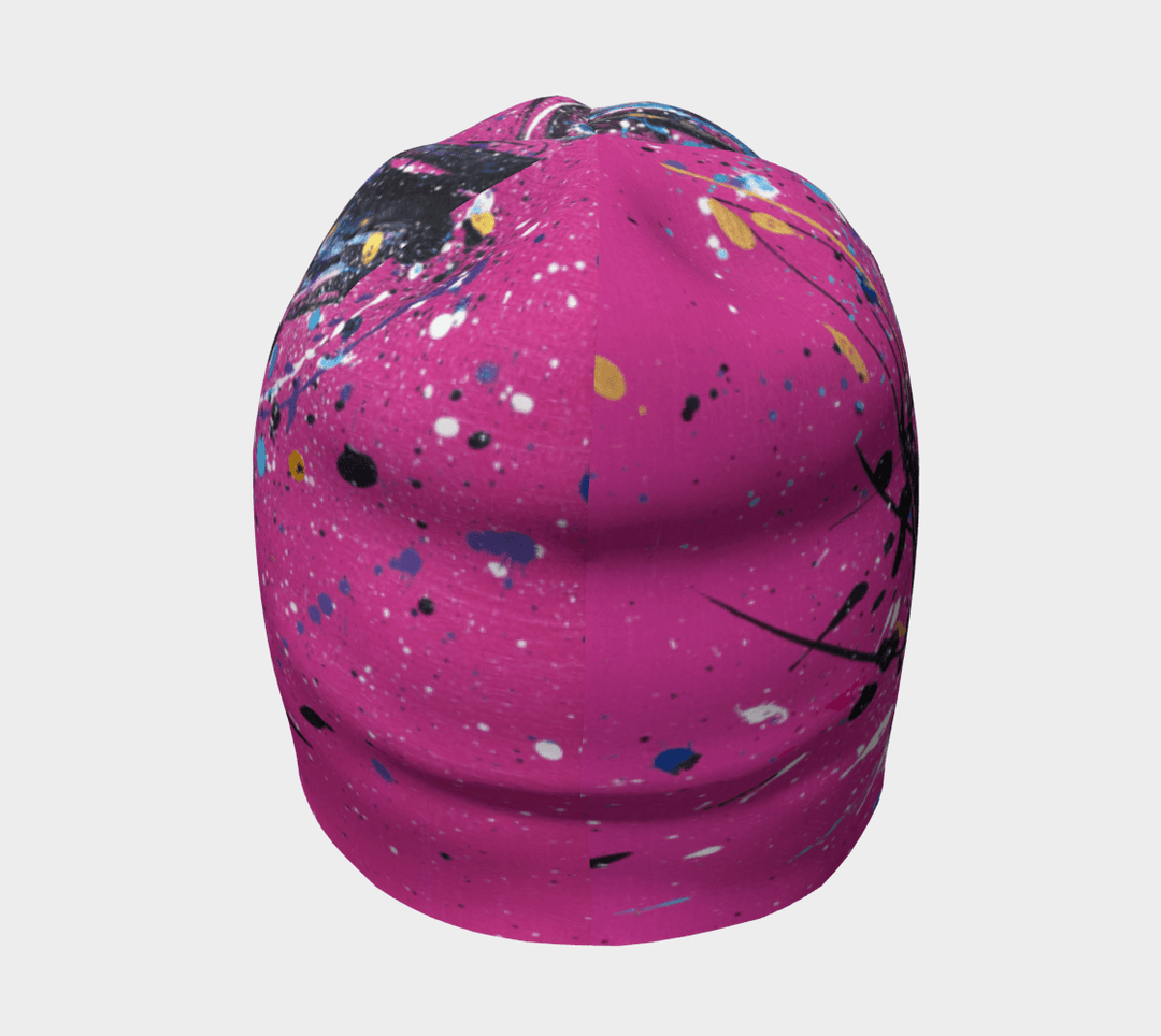 A pink beanie with an abstract paint splatter design, viewed from the front.