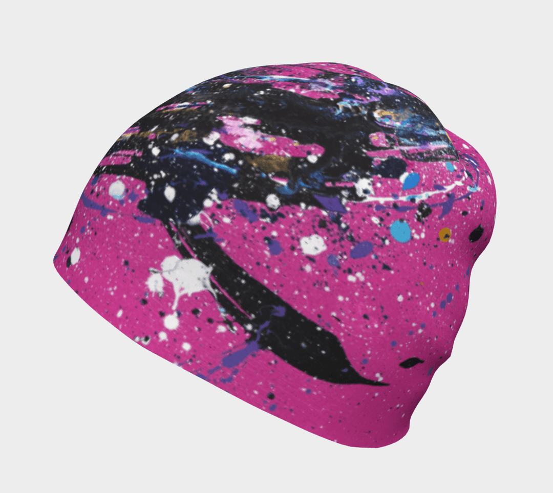 A pink beanie with an abstract black, blue, and white paint splatter design, isolated on a white background.
