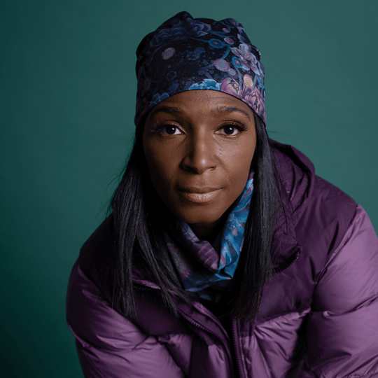 Woman wearing a purple puffer jacket, a floral beanie, and a matching floral neck warmer.