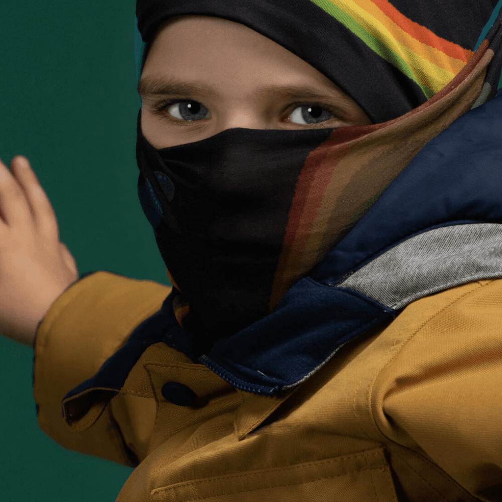 Child wearing a yellow jacket and blue beanie, with the Polar Flying Saucers Neck Gaiter pulled up as a face covering