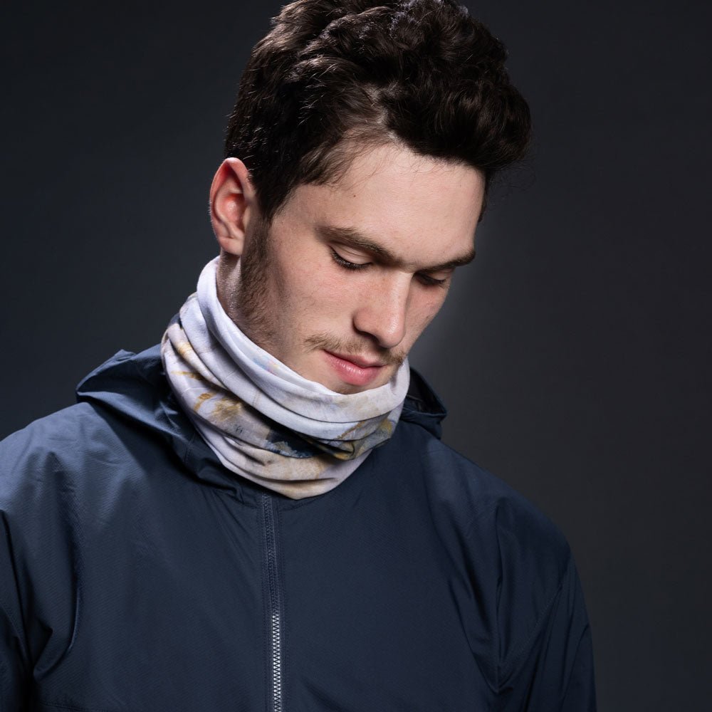 Man wearing a navy jacket, with the abstract art print neck gaiter around his neck.