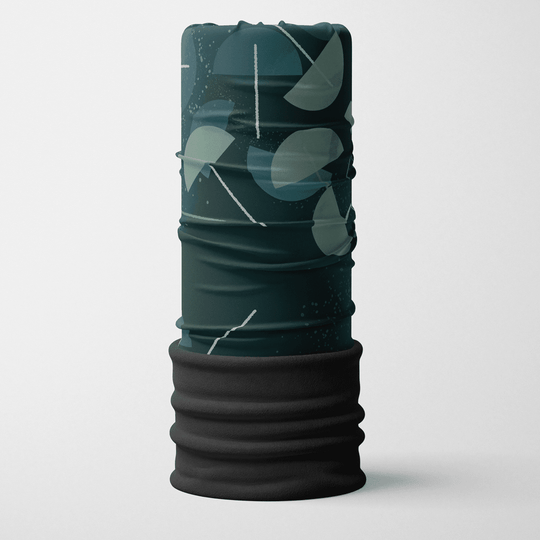 A folded, dark teal and grey abstract patterned neck tube with a black fleece band at the bottom, standing upright against a white background.