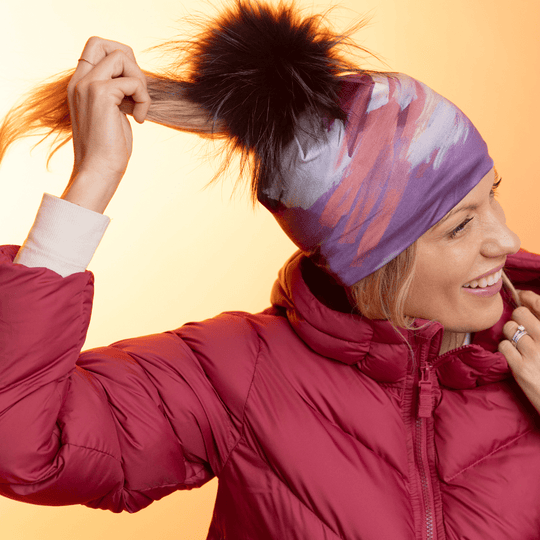 Femme portant la tuque Ponytail Tulips avec pompon noir, une veste rouge et une queue de cheval.