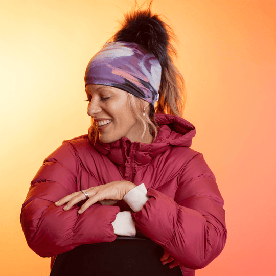 Femme portant la tuque Ponytail Tulips avec pompon noir et une veste rouge, regardant de côté.