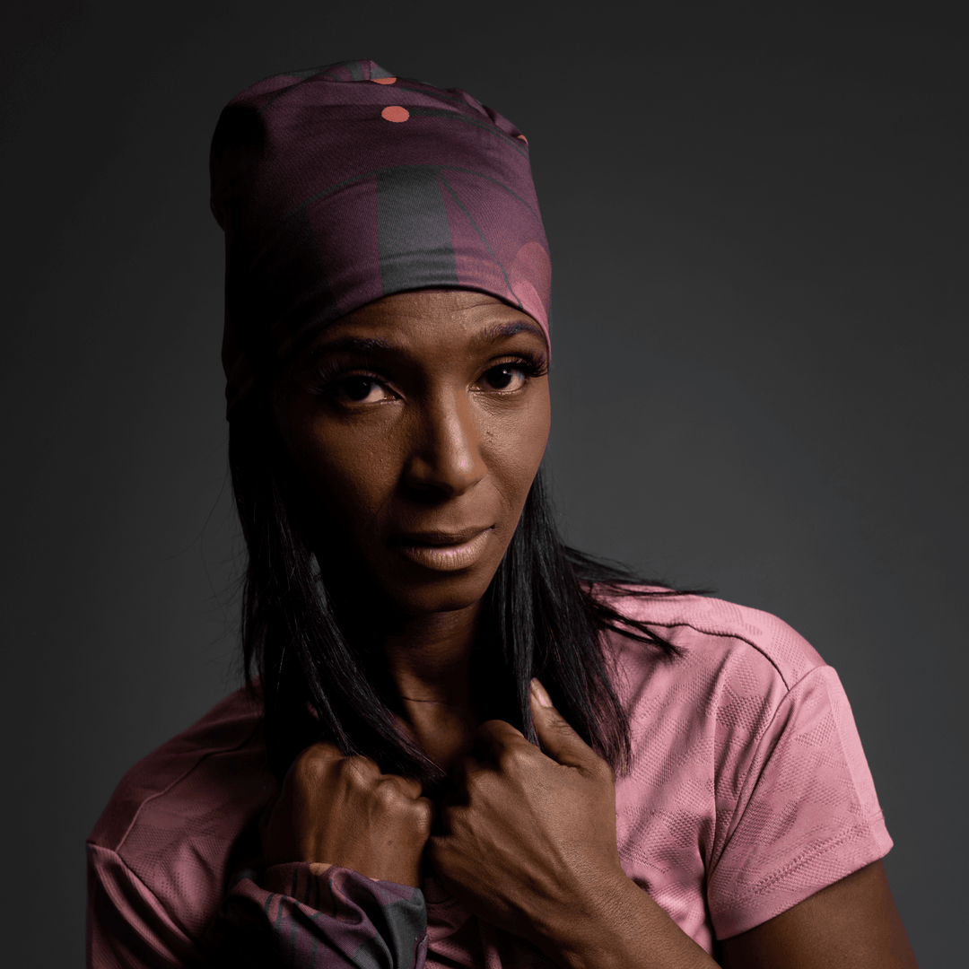 Woman adjusting her Purple Geometrics Beanie, looking away with a serious expression.