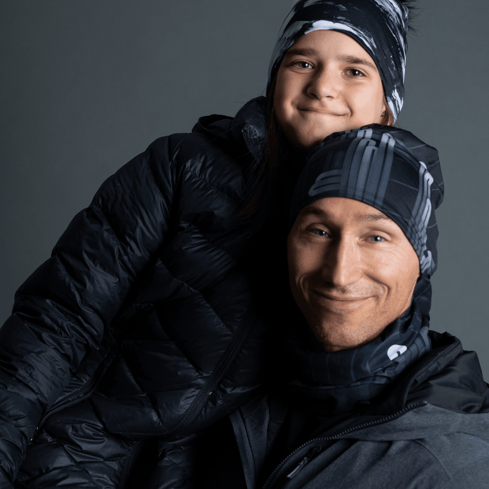 Man and child wearing matching Radio City beanies and winter jackets, smiling.