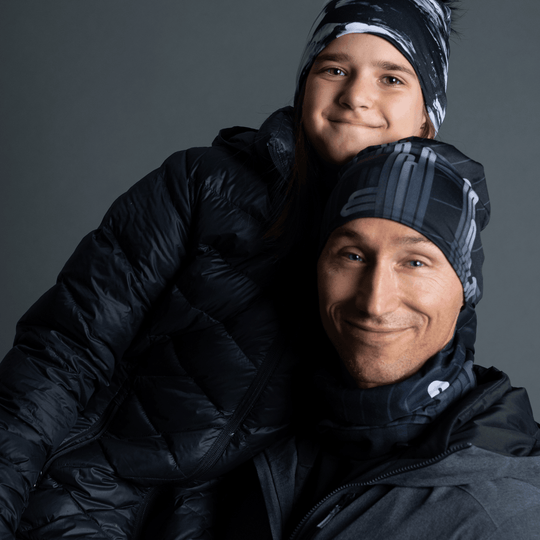Man and child wearing matching Radio City beanies and winter jackets, smiling.