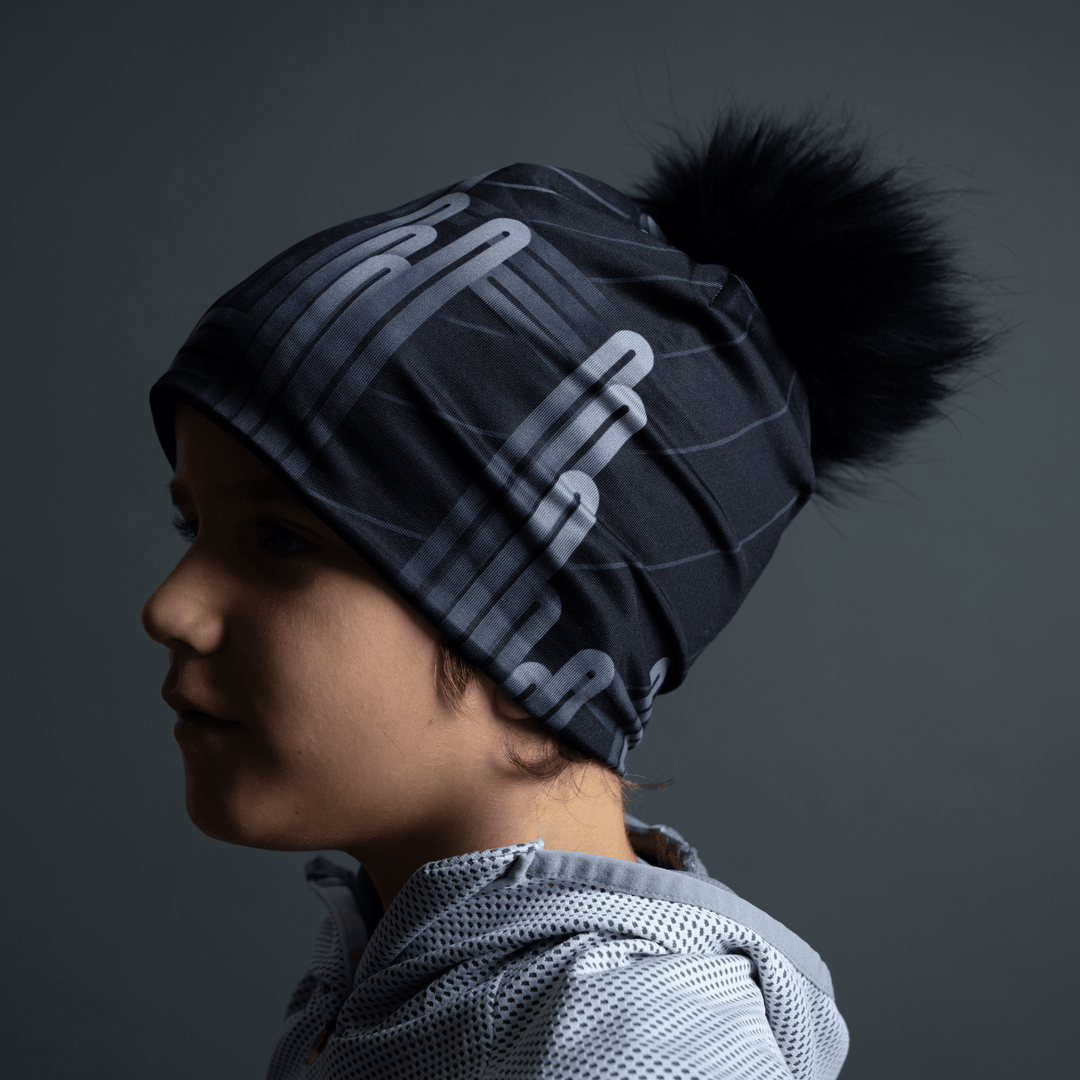 Side profile of a child wearing the black Radio City Beanie with a grey hooded jacket.