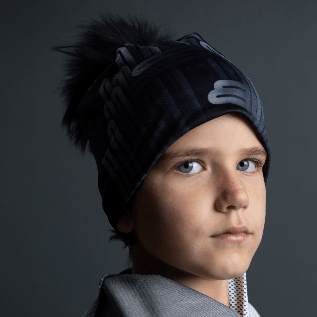 Young boy wearing the black Radio City Beanie with a grey hood, looking forward.