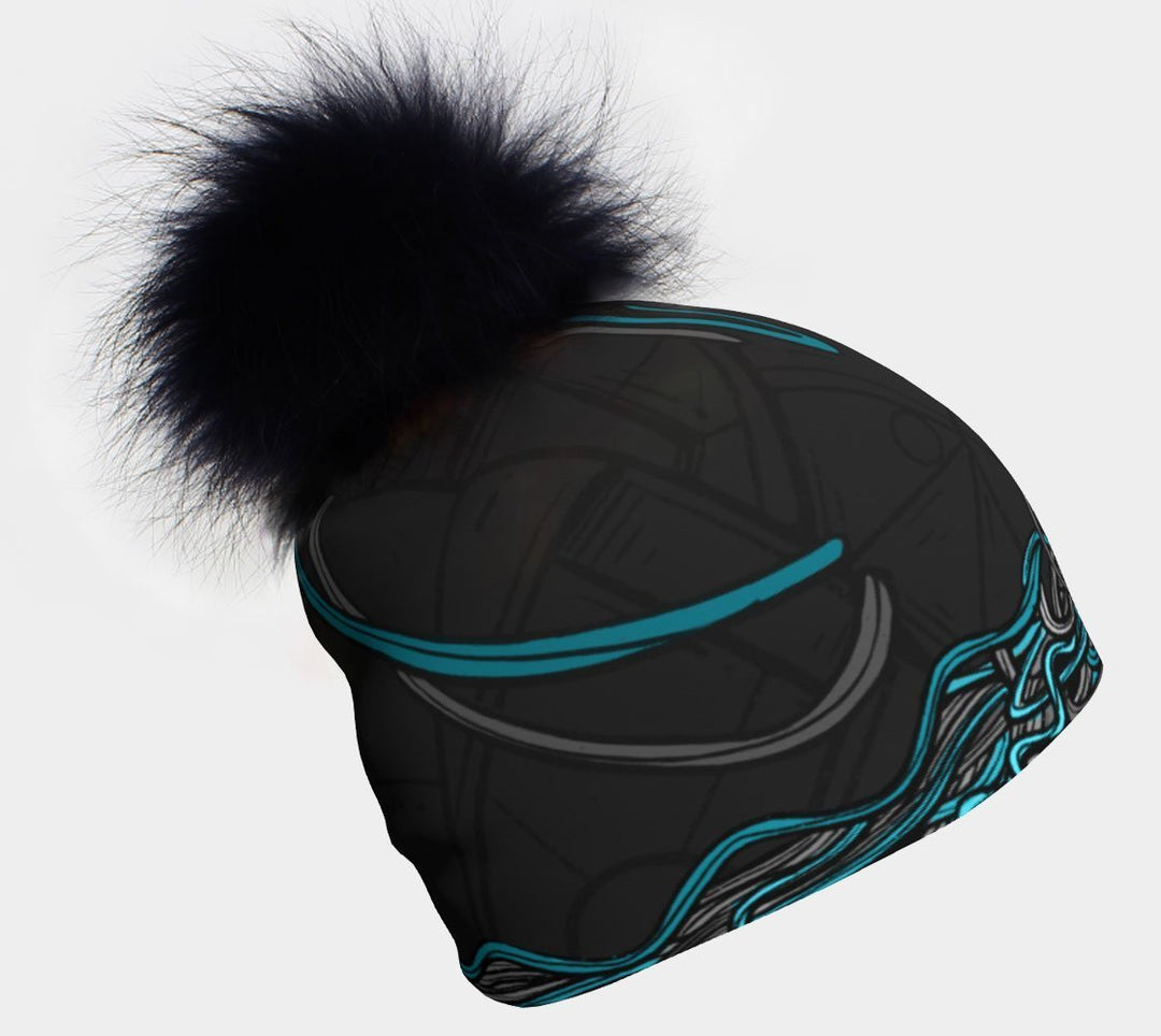 Black and blue patterned beanie with a large black fluffy pompom against a white background.