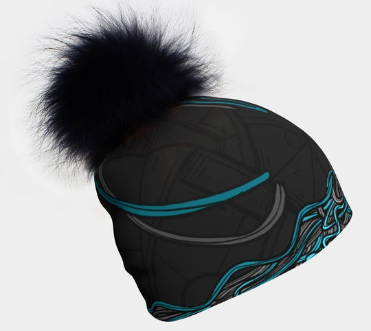 Black and blue patterned beanie with a large black fluffy pompom against a white background.