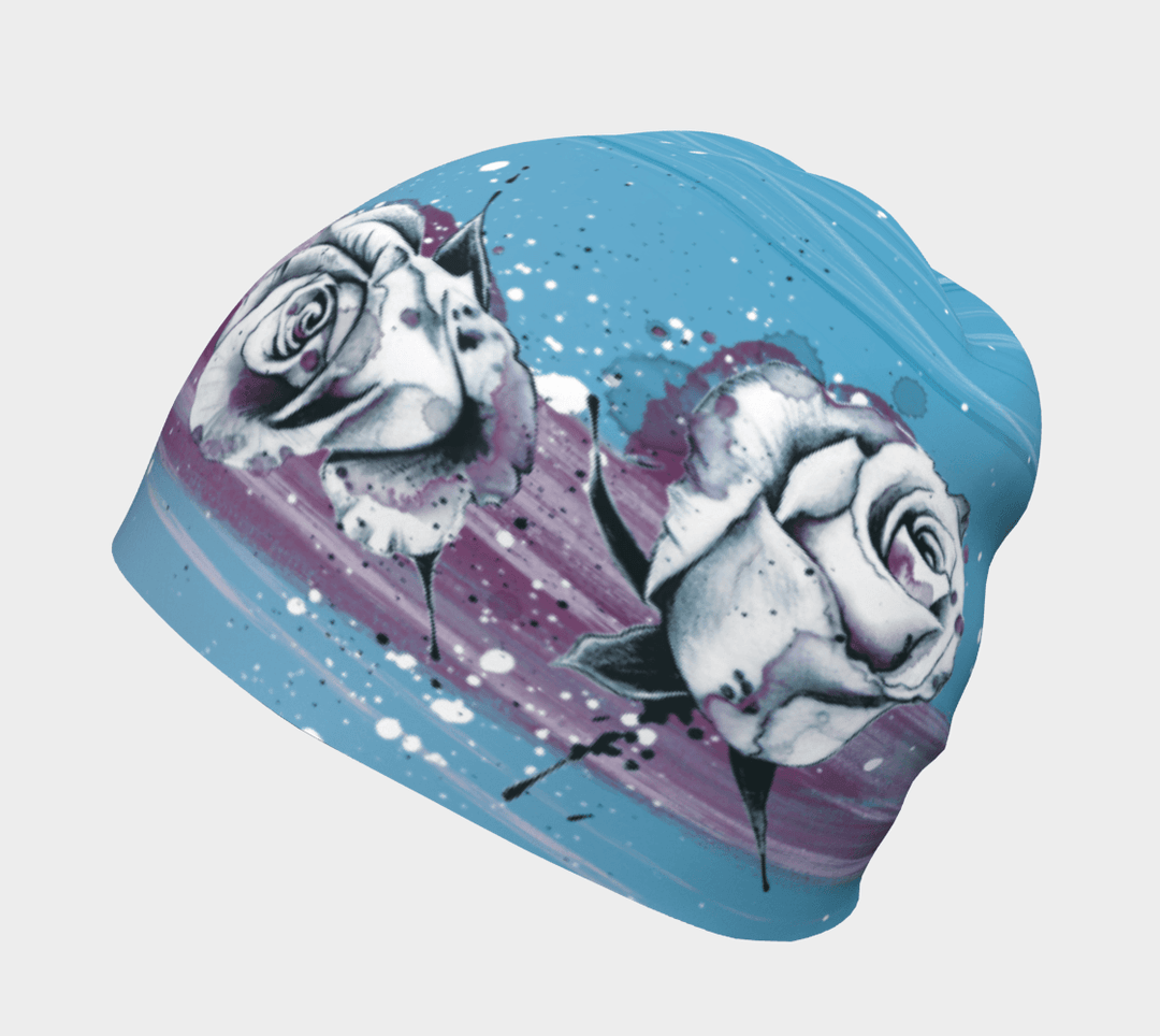 Close-up of a blue beanie with a white and purple floral watercolor design and speckles.