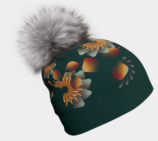 Close-up of a dark green beanie with a green and orange floral pattern and a fluffy gray pompom.