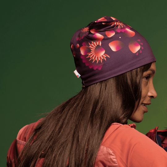 Une femme aux longs cheveux sombres portant une tuque et un cache-cou assortis à motif floral.