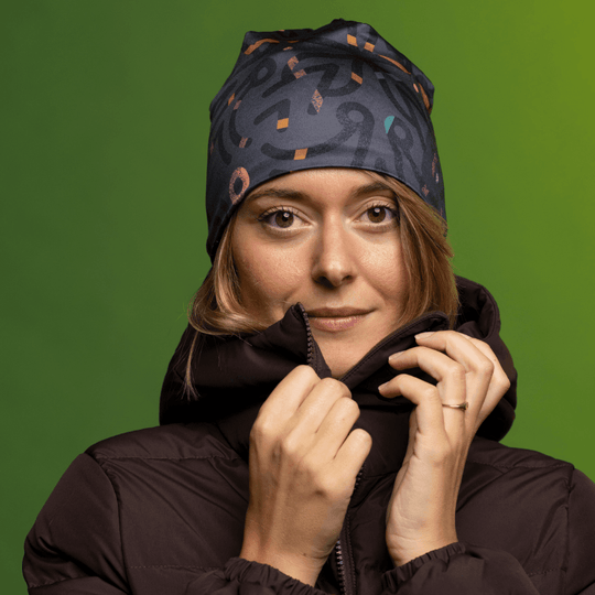 Close-up portrait of a woman wearing a gray beanie with abstract pattern and a dark brown puffer jacket.