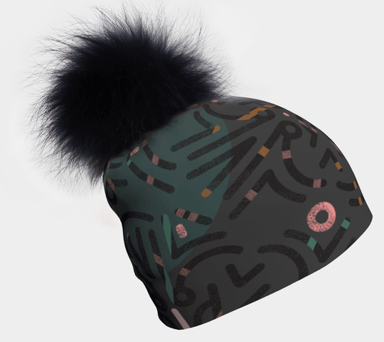 Gray beanie with a black pompom and a repeating abstract geometric pattern in dark green, pink, and orange.