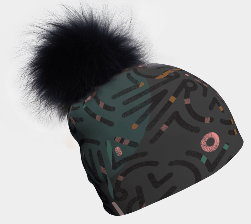 Gray beanie with a black pompom and a repeating abstract geometric pattern in dark green, pink, and orange.