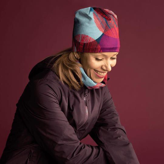 Woman wearing the Teal-Dots Beanie and a matching neck gaiter, smiling.