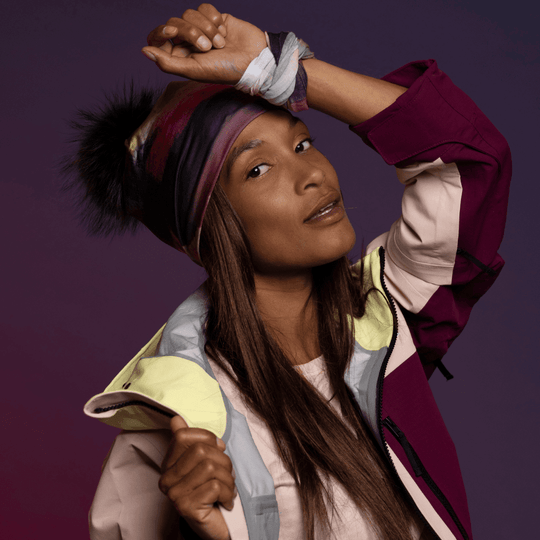 Woman wearing the abstract art beanie with a matching neck gaiter and colorful ski jacket.