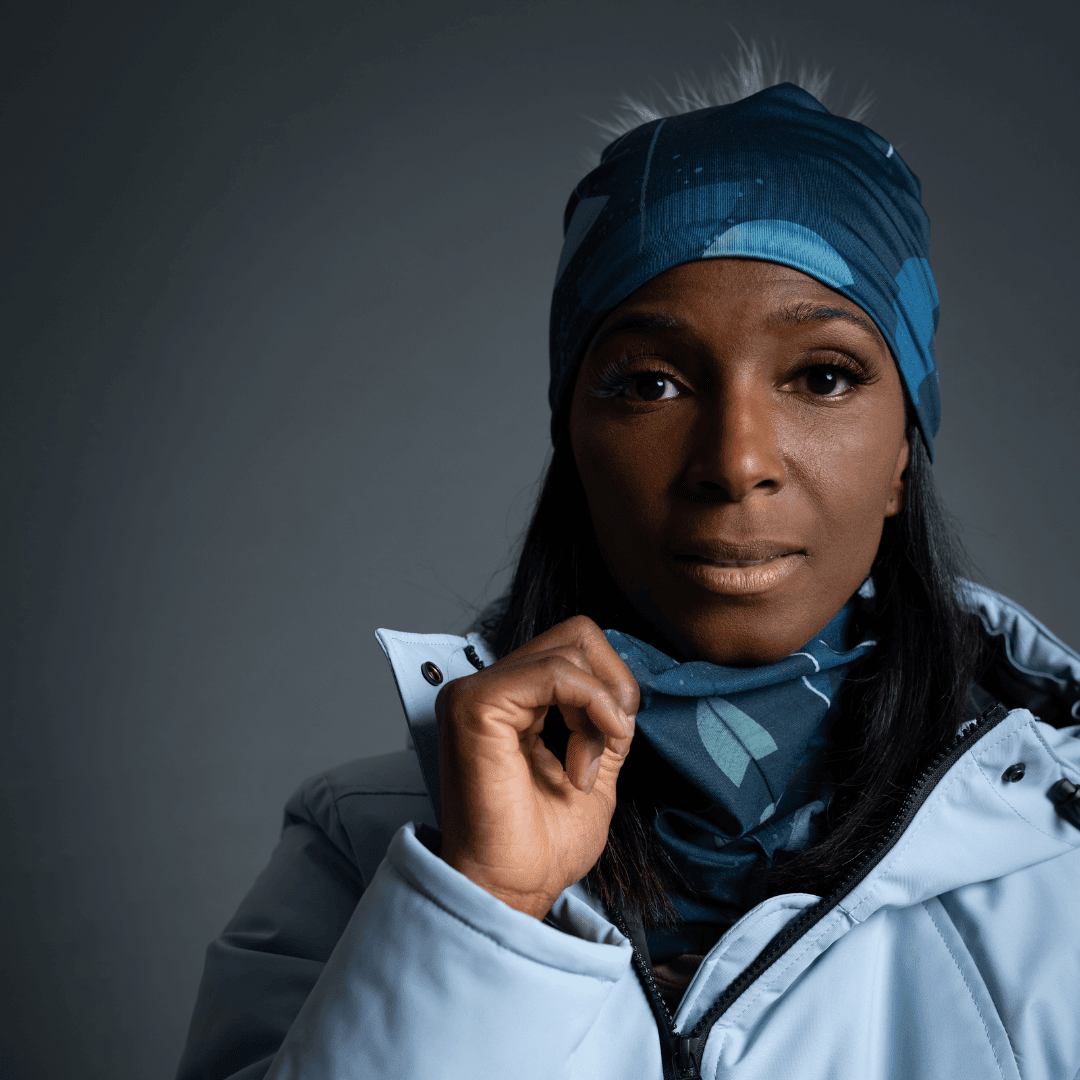 Close-up portrait of a woman wearing a light blue winter jacket and the teal beanie and neck warmer.