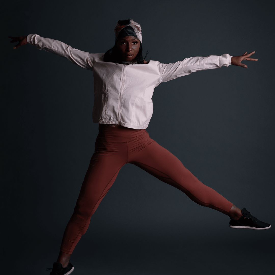 Woman in athletic wear wearing the Vie en Rose Beanie, captured mid-jump.