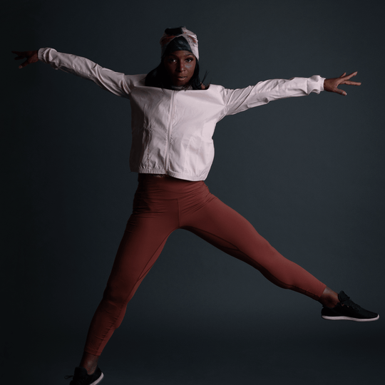 Woman in athletic wear wearing the Vie en Rose Beanie, captured mid-jump.