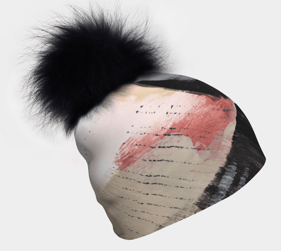 Vie en Rose Beanie with black pompom angled on a white background, showcasing abstract brushstroke art.