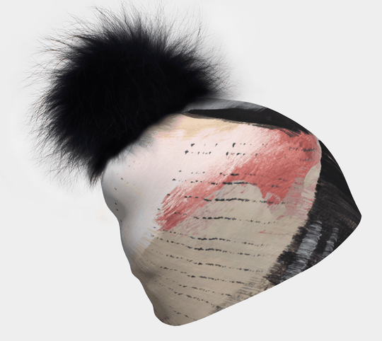 Vie en Rose Beanie with black pompom angled on a white background, showcasing abstract brushstroke art.