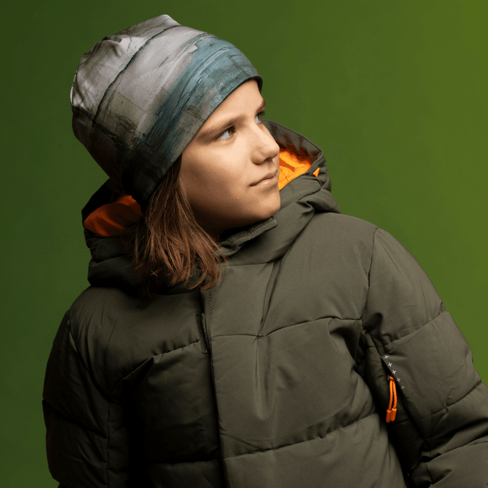 Child wearing the Wall Beanie and a green winter jacket, looking to the side.