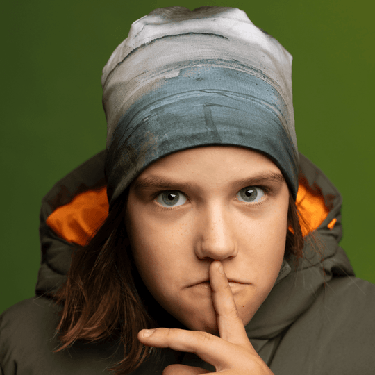 Close-up of a child wearing the Wall Beanie and green winter jacket, posing thoughtfully.