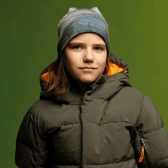 Close-up portrait of a child wearing the Wall Beanie and green winter jacket.