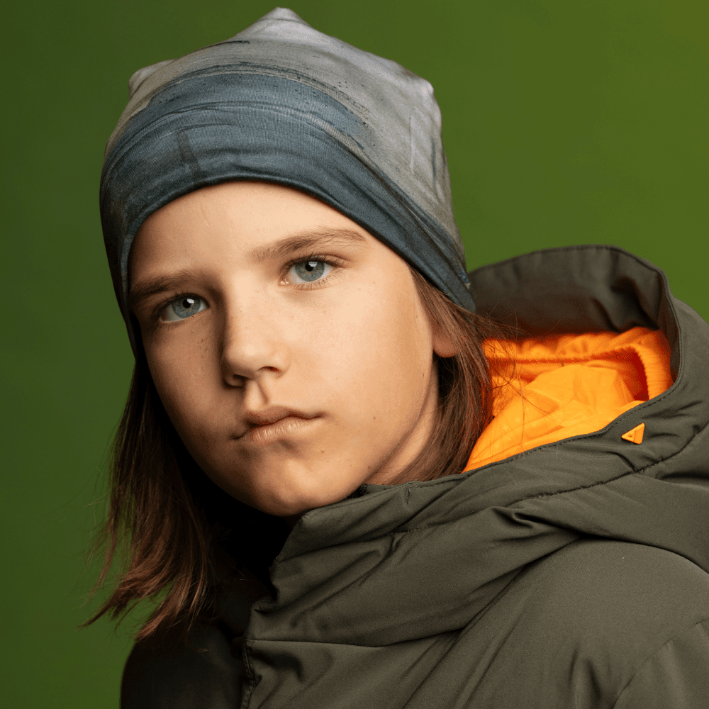 Front view of a child wearing the Wall Beanie and green winter jacket, looking directly at the camera.