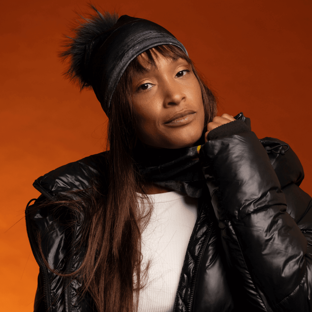 Woman wearing a black beanie with a black pom-pom and a matching neck gaiter